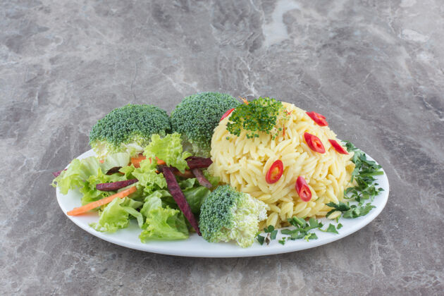 蔬菜用切碎的胡椒粉 卷心菜 青菜 胡萝卜和花椰菜装饰在大理石表面的盘子里卷心菜花椰菜配菜