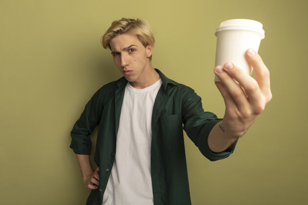 咖啡自信的金发小伙子穿着绿色t恤 端着一杯咖啡人年轻穿