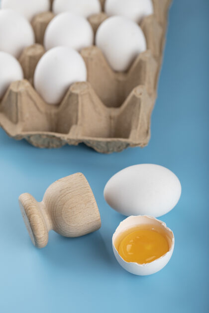 鸡蛋破碎的生鸡蛋和蓝色表面的鸡蛋容器容器烹饪破碎