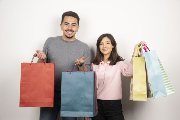 男人一对幸福的情侣 手拿购物袋站在白色的地板上夫妇关系销售