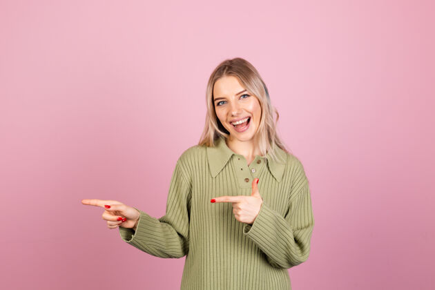 衣服漂亮的欧洲女人在粉红色的墙上穿着休闲针织毛衣手势手年轻
