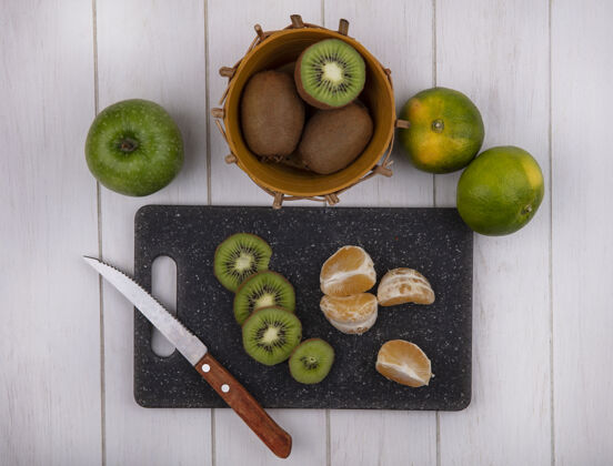 苹果俯瞰切菜板上的橘子片 篮子里放着猕猴桃 绿橘子和苹果观点水果猕猴桃
