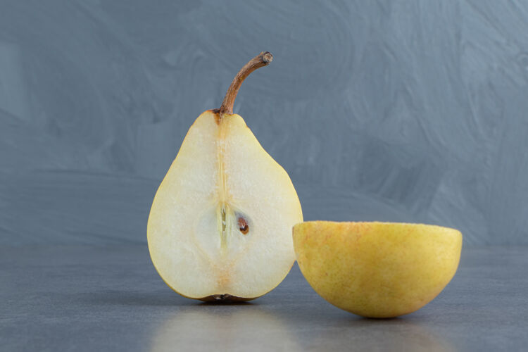 双把黄梨片隔离在灰色的表面上水果半整