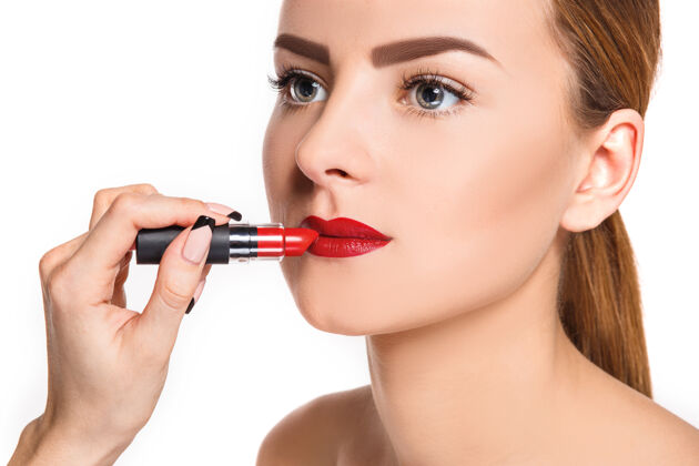 艺术家美丽的女性唇妆和白色上的红色发油化妆师的工作过程魅力手嘴唇