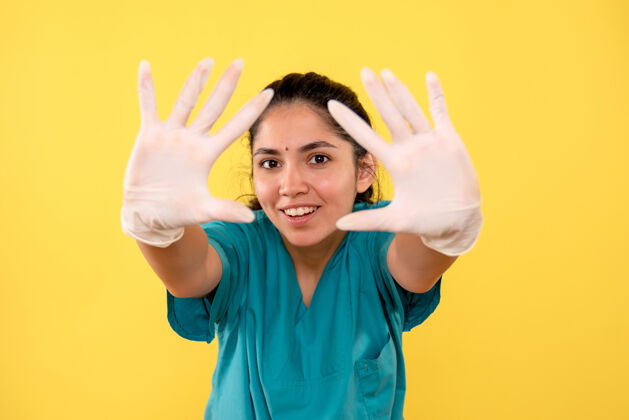女人前视图：女医生戴着乳胶手套举手年轻微笑黄色