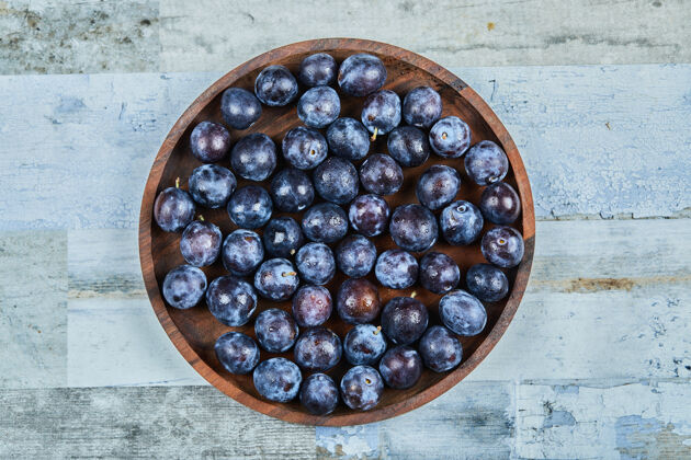 盘子花园李子在一个蓝色的背景板高品质的照片顶部水果成熟
