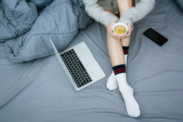 温暖在寒冷的日子里 在床上用笔记本电脑工作的女人轻松活跃工作