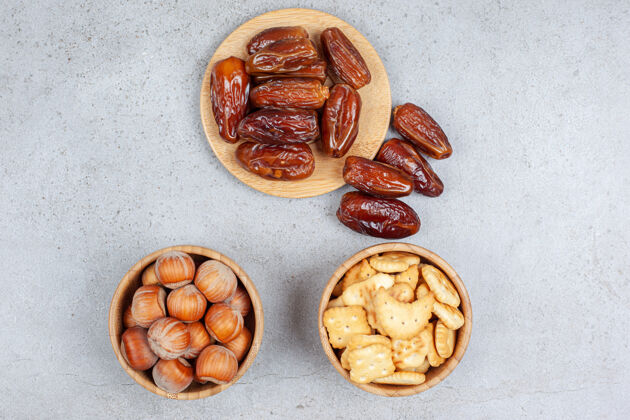 口味各种各样的枣放在木板上 坚果和饼干放在碗里放在大理石背景上高质量的照片水果减肥食品坚果