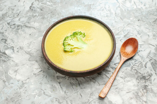 餐棕色碗里的奶油西兰花汤和灰色桌子上的勺子的侧视图热的健康碗