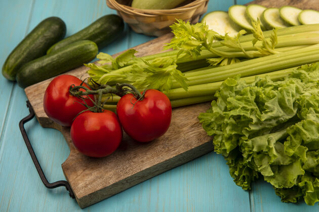 板新鲜蔬菜的顶视图 比如西红柿 芹菜和西葫芦 它们被隔离在木制的厨房板上 黄瓜被隔离在蓝色的木制背景上食品木材新鲜