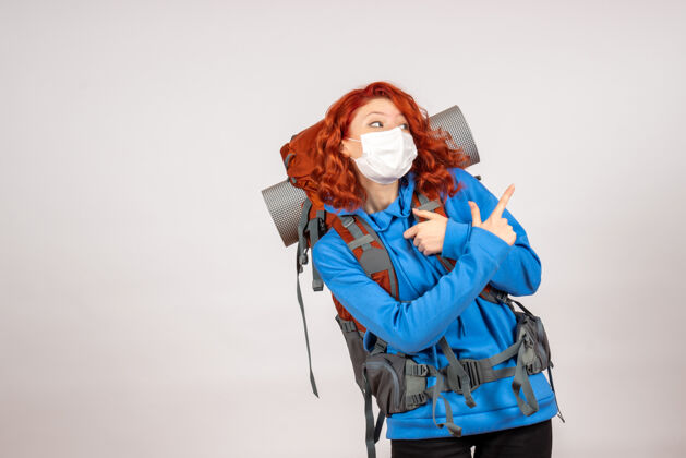 旅行戴着面具背着背包的女游客的正面图肖像自然面具