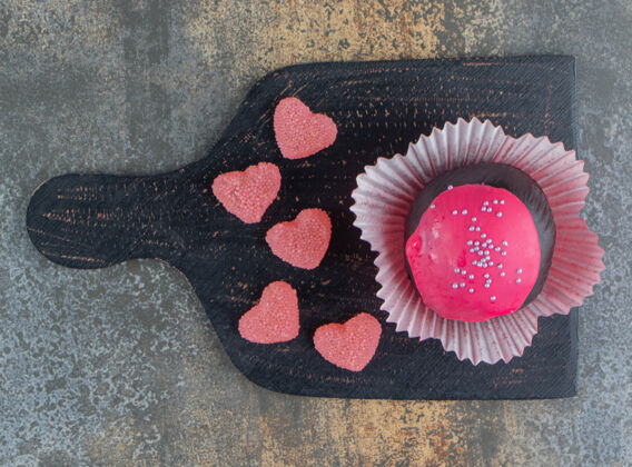 糖果巧克力饼干和粉红色釉面和糖果在木板上面包房美味巧克力