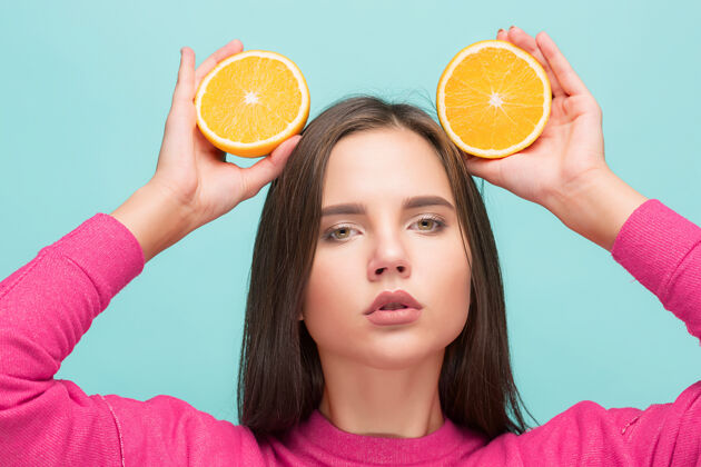年轻美丽的女人脸上有多汁的橘子多汁模特肖像