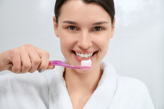 浴室浴室里拿着粉色牙刷和牙膏的女人卫生牙医漂亮