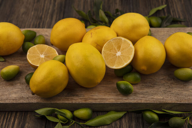 金盏花木制背景上的木制厨房板上的柑橘类水果（如金盏花和柠檬）的俯视图柑橘饮食食物