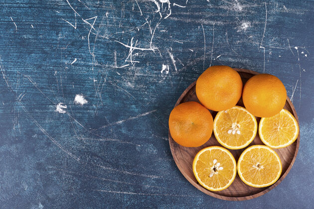 生物在蓝色背景的木盘上切橘子和柑桔高质量的照片产品健康水果