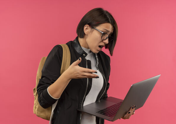 印象印象深刻的年轻学生女孩戴着眼镜 背着书包拿着笔记本电脑看着手上的空气隔离在粉红色保持笔记本电脑包