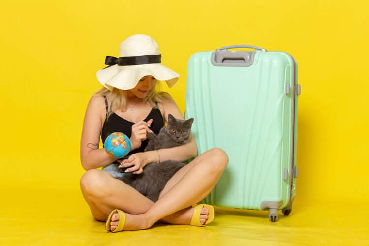 成人正面图年轻的女性坐在她的绿色袋子拥抱小猫在黄墙上旅行度假海上旅行太阳年轻风景拥抱