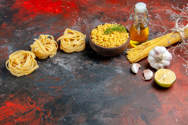 混合在一个棕色的碗里放着三份未煮的意大利面和蝴蝶面 在混色的桌子上放着一个葱柠檬蒜油瓶油碗食物