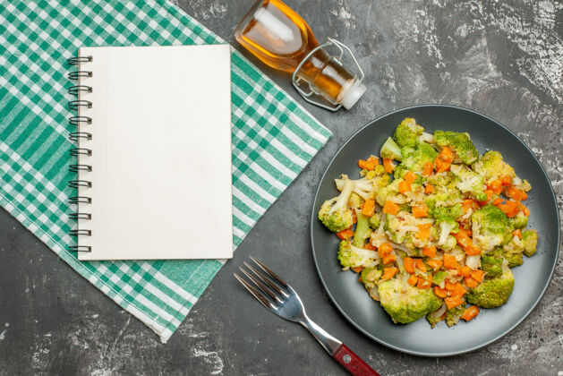 锅新鲜健康的蔬菜色拉绿条毛巾与下跌的油瓶和笔记本瓶子新鲜胡椒