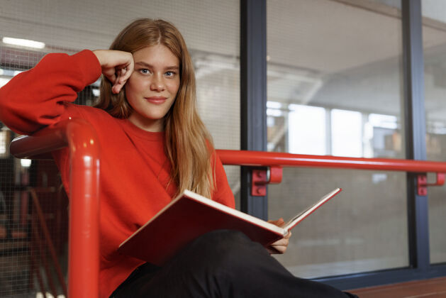 教科书聪明迷人的红发女孩 一个十几岁的学生在图书馆大厅读书年轻大学大学