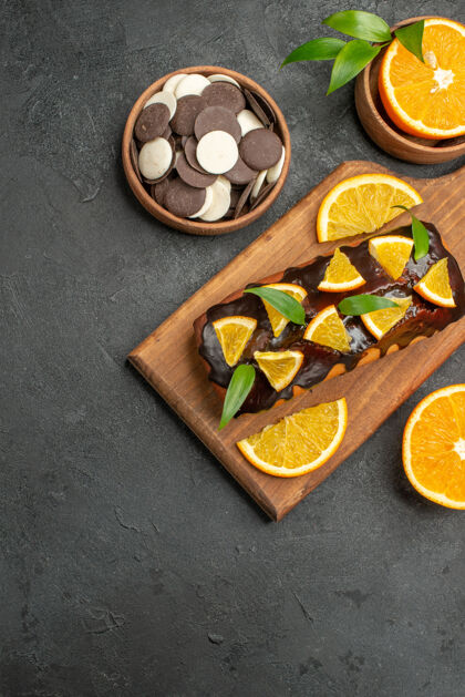 烹饪美味的蛋糕把橘子和饼干放在黑桌子上的砧板上切晚餐食宿