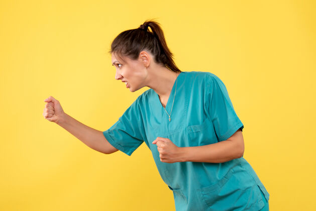 人正面图黄色背景上穿着医用衬衫的女医生威胁运动装医疗