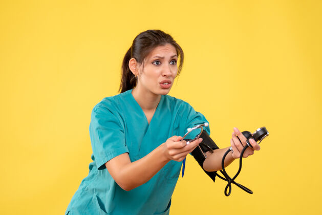 健康前视图穿着医用衬衫的女医生正在检查黄色背景上的压力前面病毒情绪