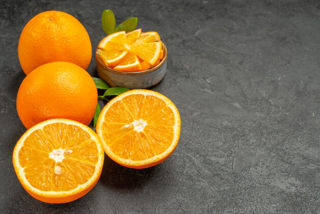 健康黑色桌子上一套黄色的整片橙子和切碎的橙子的水平视图甜橙可食用水果果汁