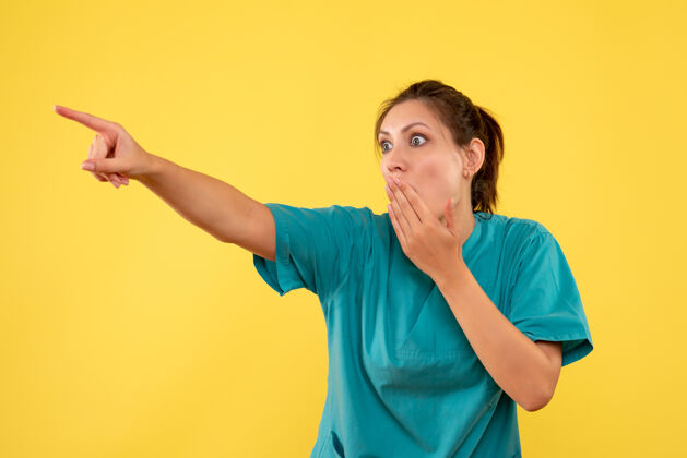 护士前视图穿着医用衬衫的女医生在黄色背景上看着一张震惊的脸病毒成人人