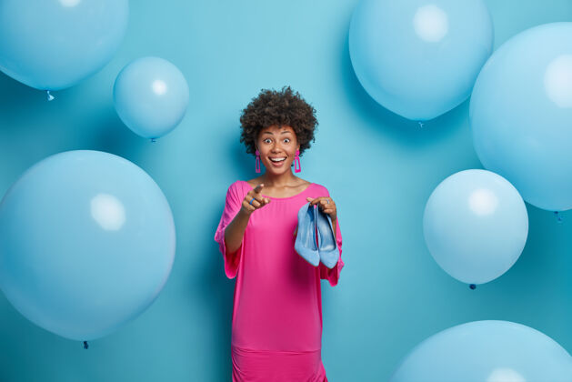 充气时尚的美国黑人女士在粉红色的裙子举行最后的趋势蓝色鞋点在前面 并提出了大气球周围时尚的概念聚会心情女性