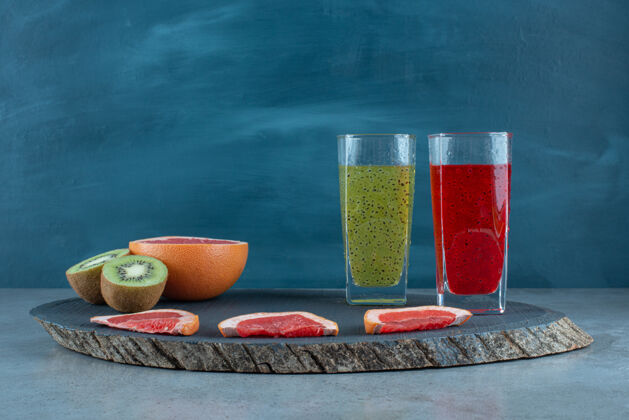 木材两杯新鲜果汁和各种水果片葡萄柚杯子板