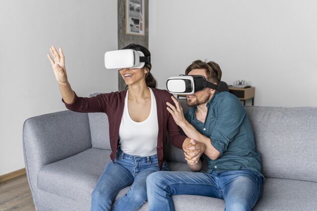 休闲男人和女人在家里的沙发上与虚拟现实耳机乐趣虚拟现实虚拟现实眼镜