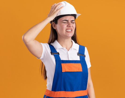 建筑工人闭眼遗憾的是 年轻的建筑女工穿着制服被隔离在橙色的墙上年轻关门了制服
