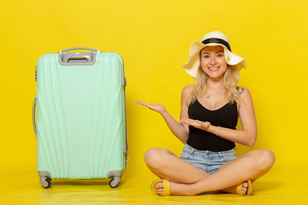 视图正面图年轻的女性坐在她的绿色袋子感到快乐的黄墙旅行度假太阳旅行成年人公文包笔记本电脑