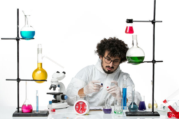 玻璃白壁上工作过程中身着特殊服装的年轻男科学家的正面图研究工艺瓶子