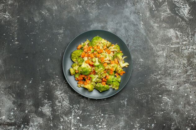 厨具在灰色桌子上的黑色盘子里放上西兰花和胡萝卜的健康餐平底锅晚餐豆类