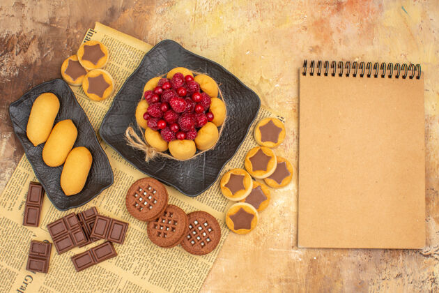 早餐美味的蛋糕不同的饼干放在棕色的盘子里 笔记本放在五颜六色的桌子上蔬菜美味的蛋糕饮食