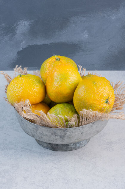 柑橘在灰色背景上放满了橘子（橘子 桔子 柑橘类水果）的铁碗灰色自然配料