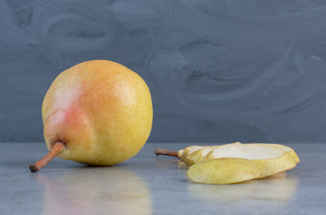 风味梨片排在大理石背景上的一整颗梨旁边梨美味健康