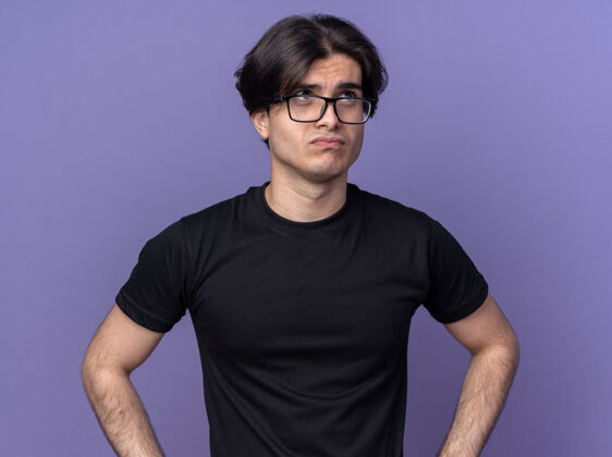 思考一个穿着黑色t恤和眼镜的年轻帅哥被隔离在紫色的墙上眼镜T恤年轻人