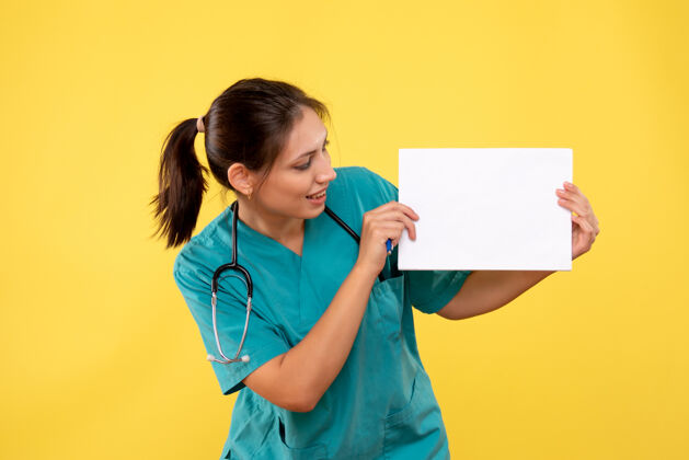 健康正面图黄色背景下穿着医疗衫的女医生拿着纸分析女医生衬衫正面