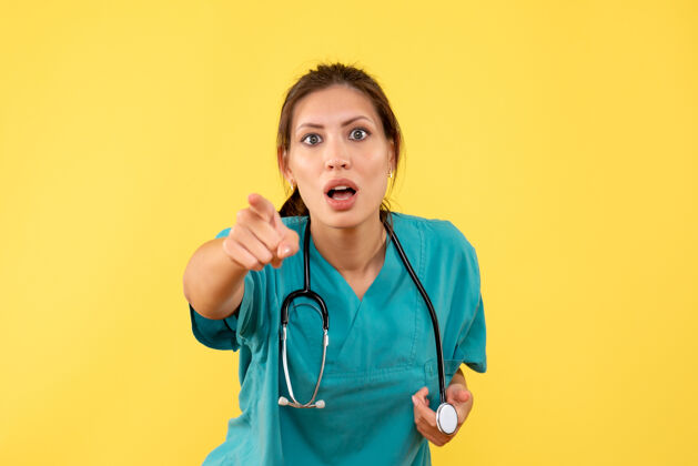 健康正面图黄色背景上穿着医用衬衫的女医生惊讶不已病毒惊喜视图