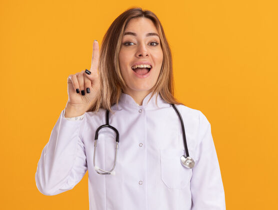 穿印象深刻的年轻女医生穿着医用长袍 用听诊器指着隔离在黄色墙上的那堵墙听诊器点医生