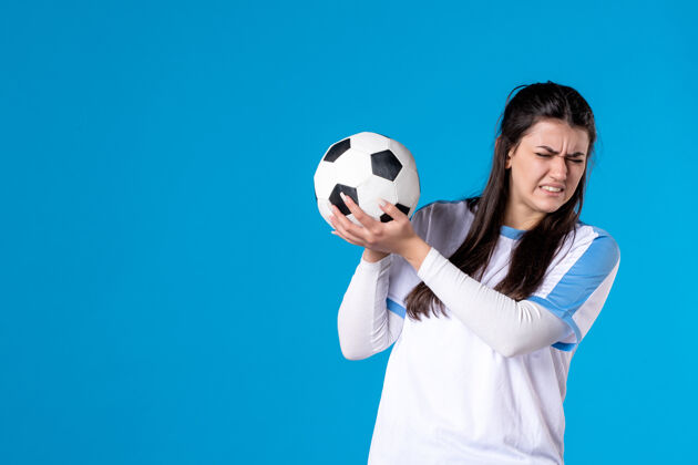 竞争前视图：蓝色墙上有足球的年轻女性充满活力事件青年