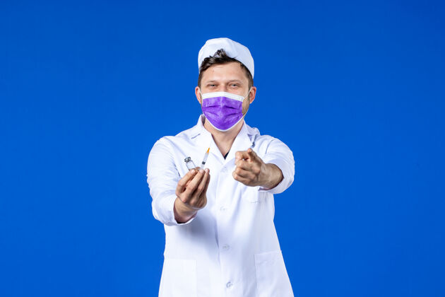 药品男医生的前视图 穿着医疗服 戴着蓝色的注射和疫苗面罩外套男医生注射