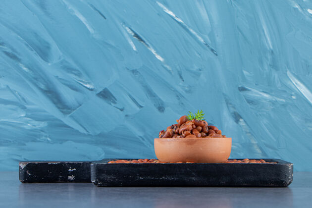 自制豆子碗在豆子板上 在蓝色的背景上生的美味的餐盘