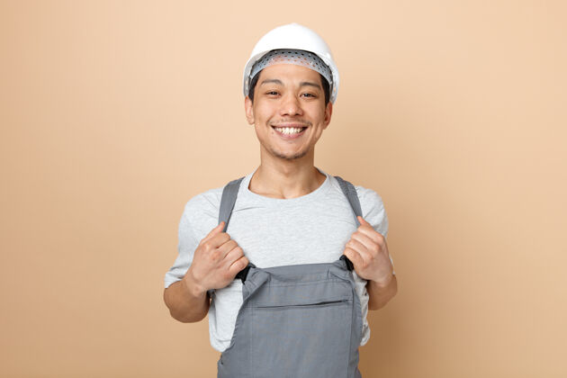 制服快乐的年轻建筑工人戴着安全帽和制服抓起他的制服施工年轻安全