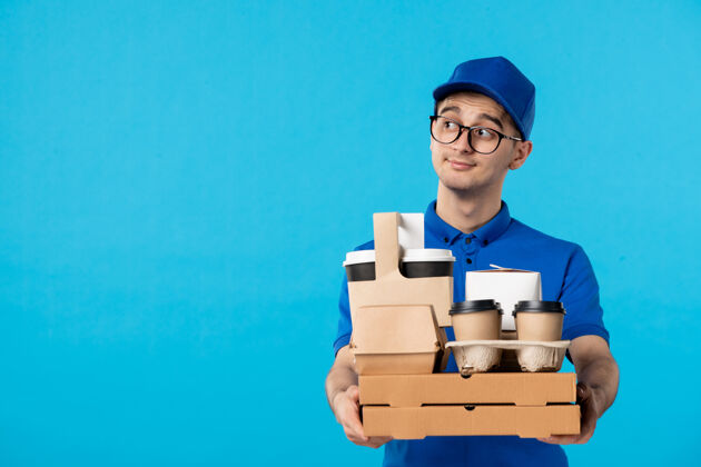 学生身穿蓝色制服的男快递员的正面图 咖啡和披萨是蓝色的送货工作服务