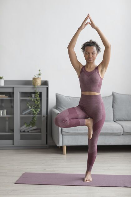 灵活健身女士在家里用瑜伽垫做瑜伽心灵和平内心的和平